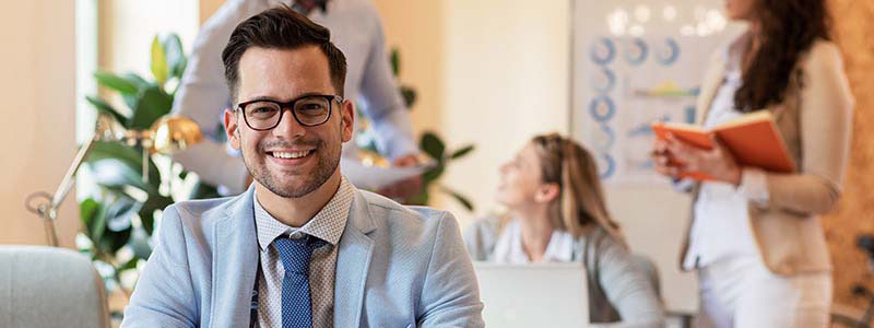 Hombre de traje y corbata, con lentes y sonriendo