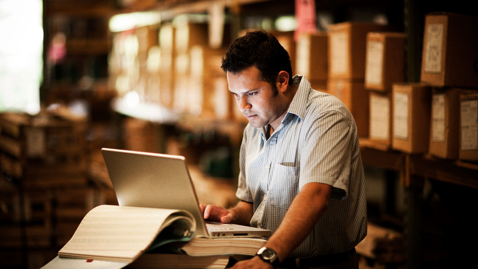 hombre trabajando con su laptop en almacén