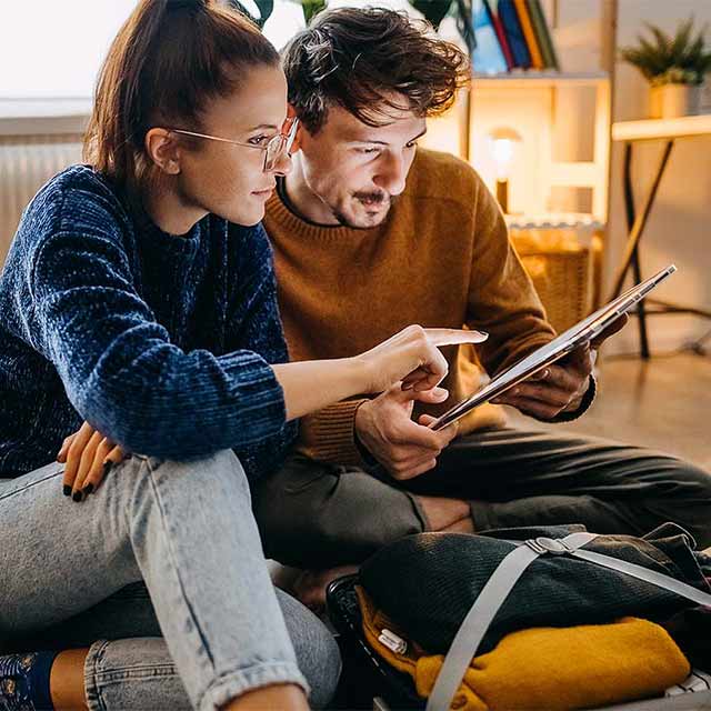 Pareja preparada para viajar revisando su itinerario en una tablet