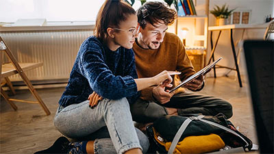 Pareja preparada para viajar revisando su itinerario en una tablet